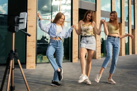 Three young women dancing and filming outdoors