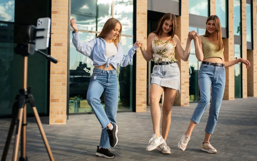 Three young women dancing and filming outdoors