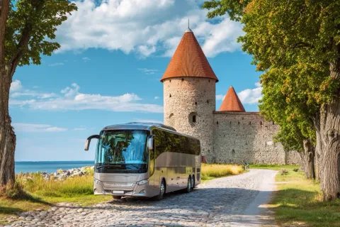Tour bus parked beside a stone castle
