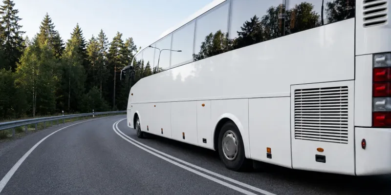 Valge buss kurvilisel metsateel