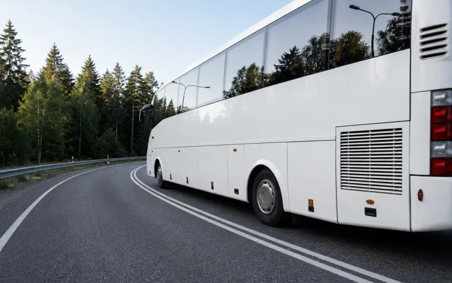 Valge buss kurvilisel metsateel