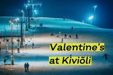 Floodlit ski slope with skiers at night